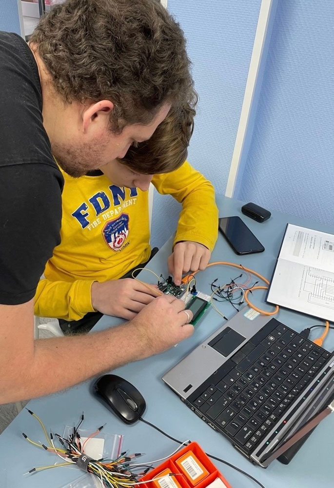 преподователь помогает ученику со сборкой схемы на Arduino