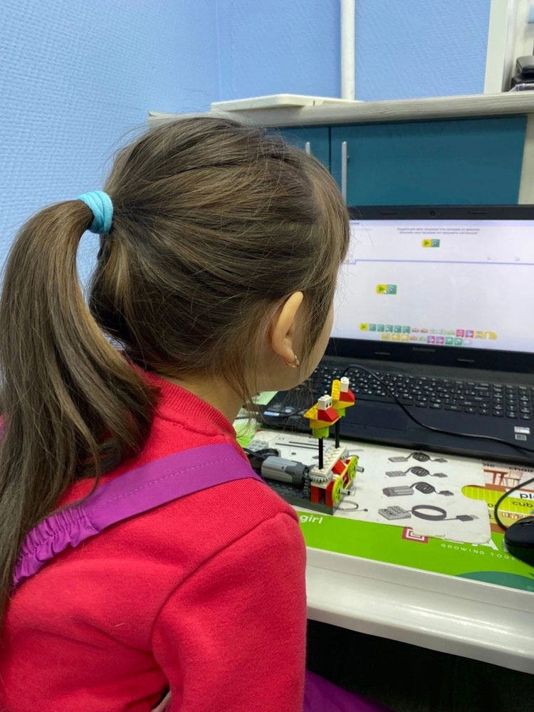 ученик собирает и программирует робота на WeDo